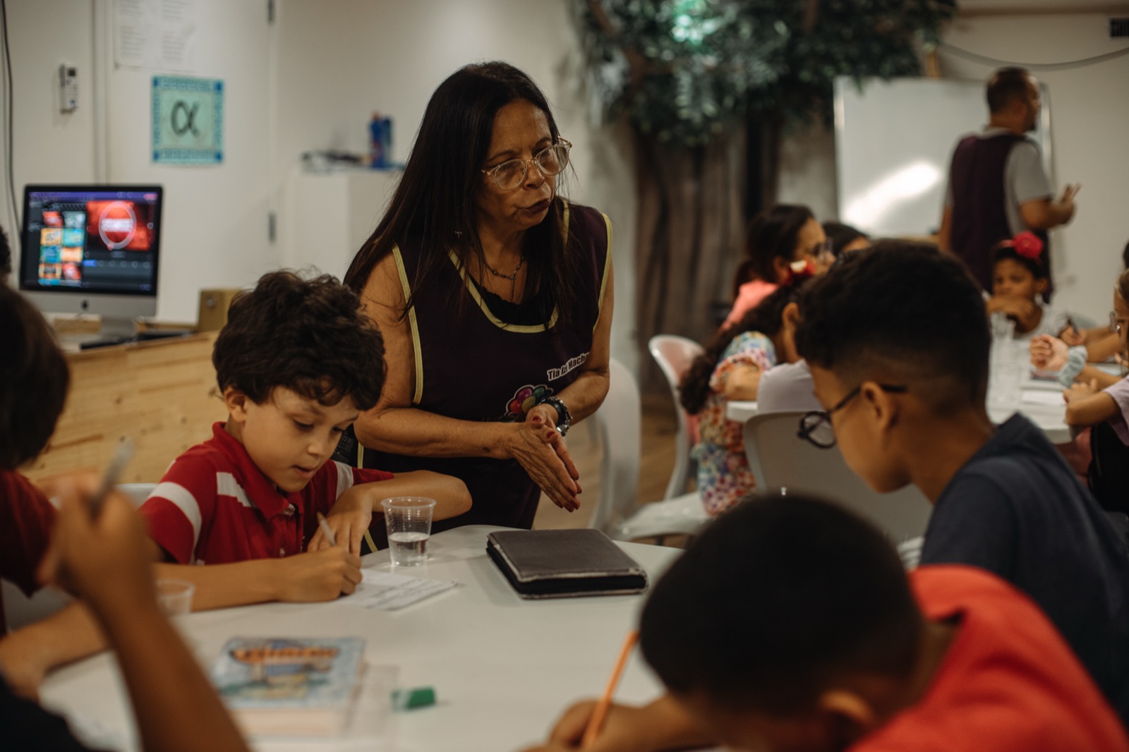 Voluntária com crianças numa mesa de atividades